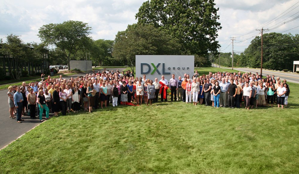 Destination XL employees pose in front of the new sign outside the company’s headquarters on Turnpike Street.