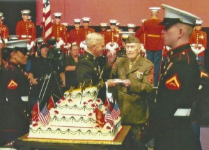 George Sykes (center) accepts a piece of cake from Gen. James Amos, commandant of the Marine Corps.