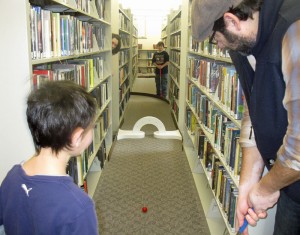 A family watches dad make a shot through the stacks.