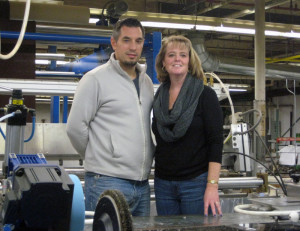 Product Manager Paul Medeiros and President Kristin Draper stand on the operator's perch of Draper's new dryer. 