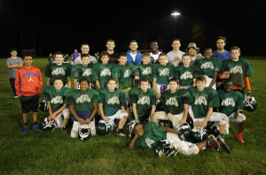 Players and coaches from the Pop Warner C team pose for a photo with Devin McCourty of the New England Patriots.